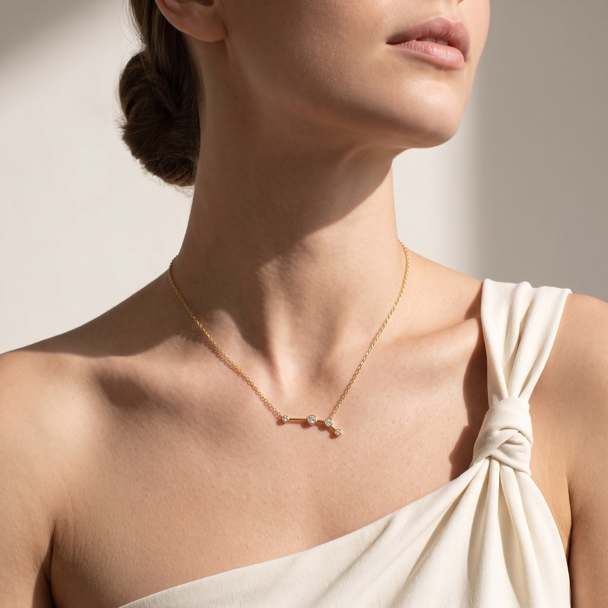 Aries constellation necklace worn with an ivory one-shoulder blouse