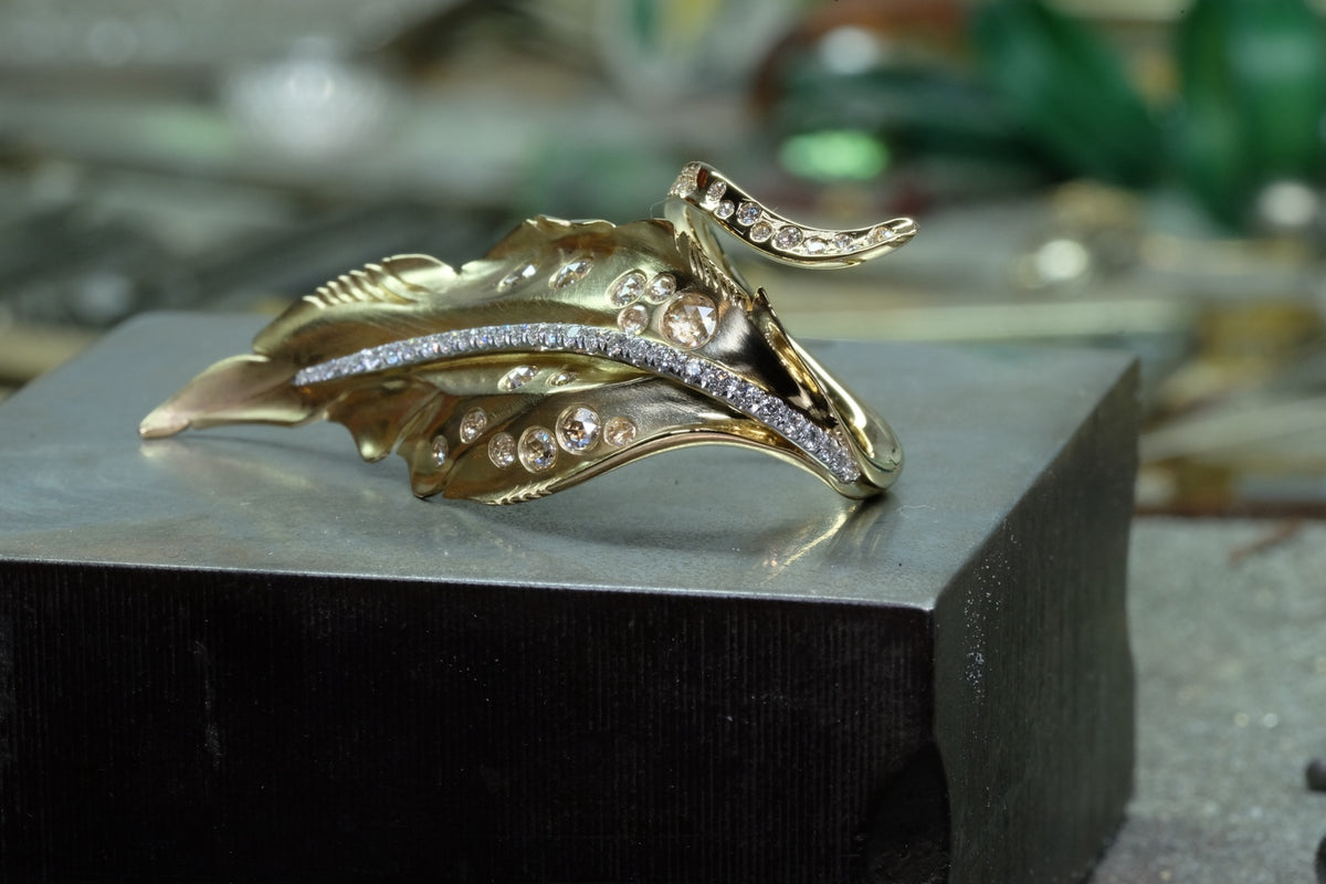 Feather-inspired 18k yellow gold ring with diamonds, angled view