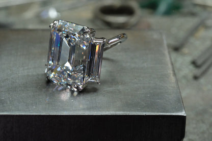 Platinum emerald-cut diamond ring with tapered baguette side stones, angled view