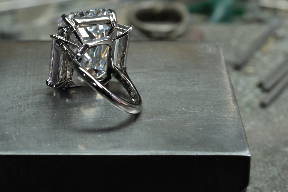 Platinum emerald-cut diamond ring with tapered baguette side stones, angled platinum band