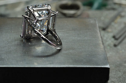 Platinum emerald-cut diamond ring with tapered baguette side stones, angled platinum band